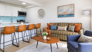 Una cocina moderna con armarios blancos, microondas y una zona de bar con taburetes.