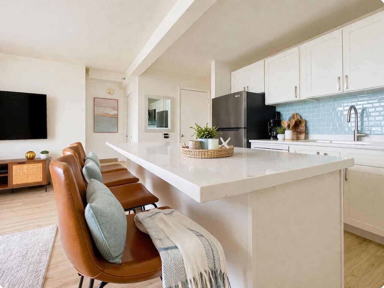 A modern kitchen with white cabinets, a black refrigerator, and a white countertop.
