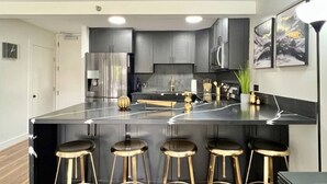 A modern kitchen with a central island, bar stools, and a coffee machine. - Tropical Oasis, Steps away from Waikiki Beach, Free Parking (Honolulu)