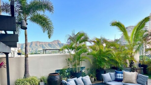 A rooftop patio with a sofa set, planters, and a view of mountains. - Tropical Oasis, Steps away from Waikiki Beach, Free Parking (Honolulu)
