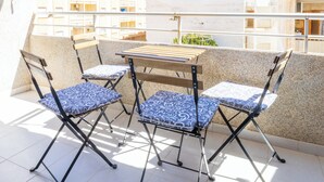 A balcony with a table and four chairs, a striped awning, and a view of buildings in the background. - 2-bedroom Apartment-close to Beaches and Center (Torrevieja)