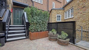 A brick building with a green door, a staircase, and potted plants. - The Carlton Tavern Hotel (London)