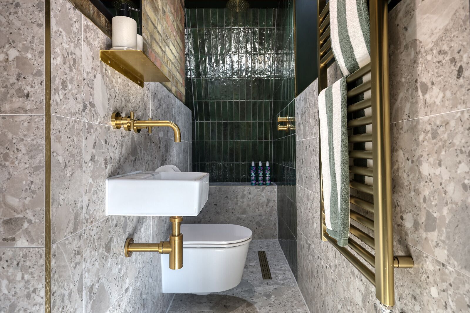 Un baño con lavamanos blanco, detalles dorados y un inodoro.