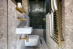 A bathroom with a white sink, gold fixtures, and a toilet. - The Carlton Tavern Hotel (London)