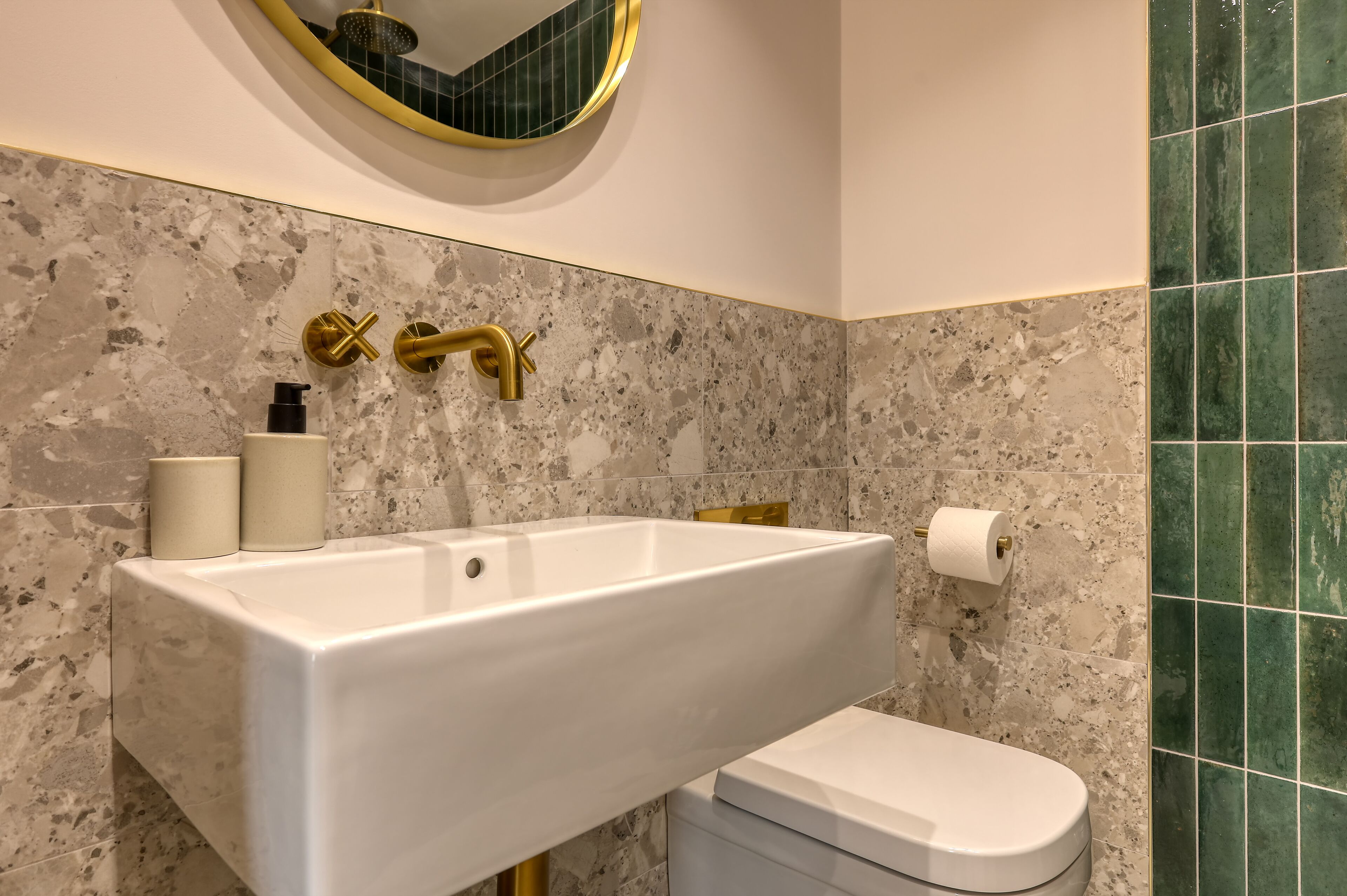 Une salle de bain avec un lavabo blanc, des robinets dorés et des toilettes.