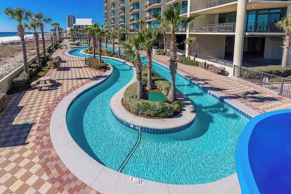 A swimming pool with a checkered walkway, palm trees, and a beachfront view.