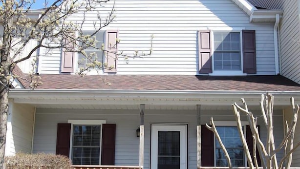 A two-story house with a front porch, a door, and a small staircase leading to the entrance. - King Charles Avenue 408 #2 (Rehoboth Beach)