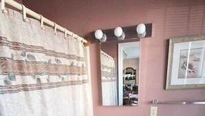 A bathroom with a shower curtain, a sink, a mirror, and a toilet. - King Charles Avenue 408 #2 (Rehoboth Beach)