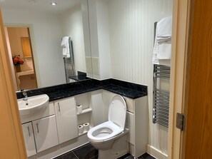 A modern bathroom with a white toilet, a black marble countertop, and a white sink. - 1-bed Apt, Sleeps 4, Central To Shops & Transport (London)