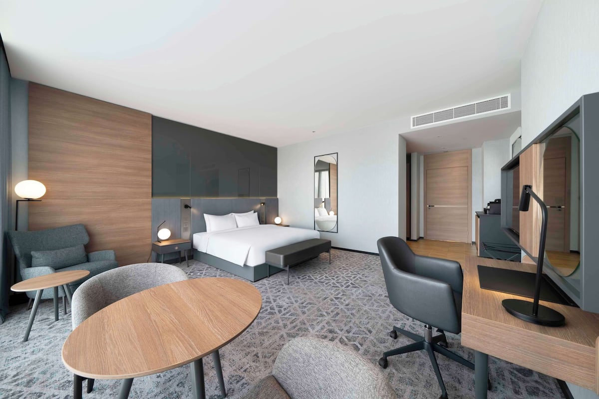 Una habitación de hotel moderna con una cama grande, un escritorio, una silla, un sofá y una pequeña mesa.