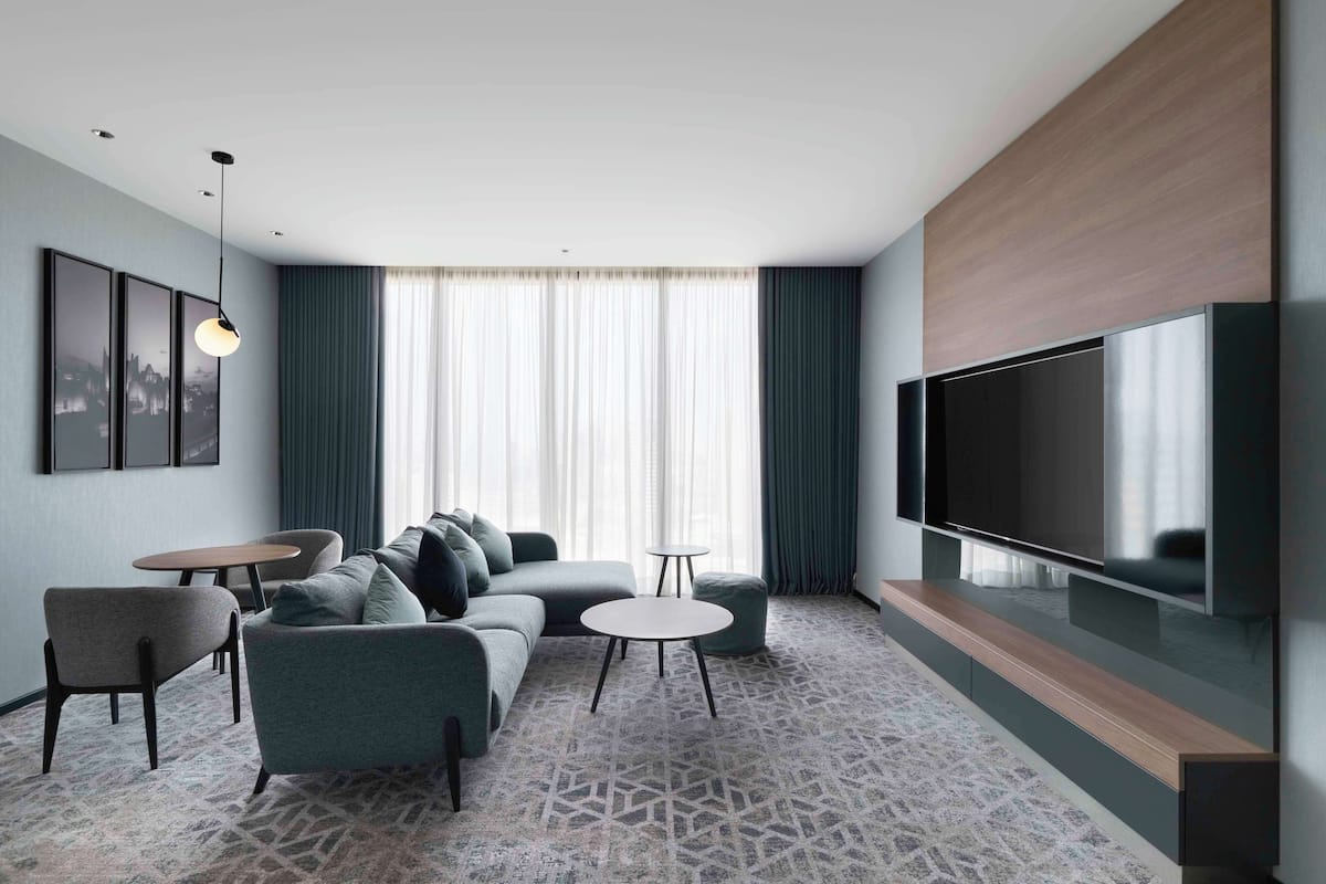 Una sala de estar moderna con un sofá modular, un televisor y una alfombra estampada.