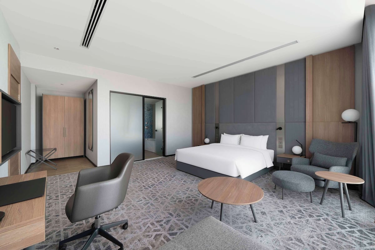 Una habitación de hotel moderna con una cama grande, un escritorio, una silla y una mesita.