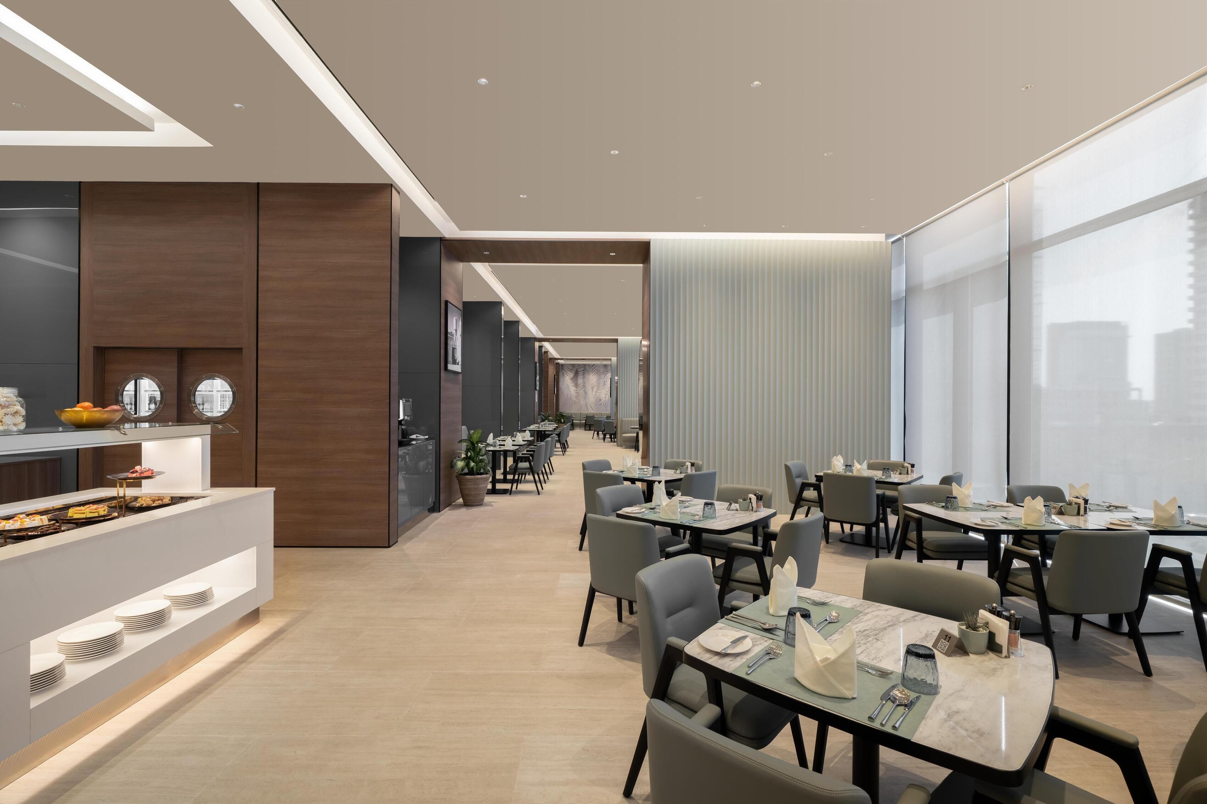 Un espace repas moderne doté d’un long comptoir, de plusieurs tables et de chaises.