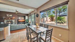 Amplia sala de estar con chimenea, una mesa de comedor y un ventanal con vistas al exterior.