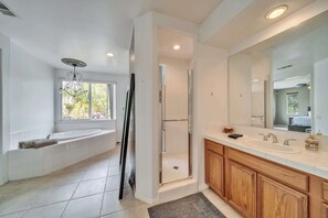 Un baño moderno con una bañera grande, ducha a ras de suelo y tocador con espejo.