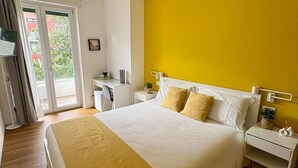 Ein Schlafzimmer mit einem Bett, Nachttischen, einem Schreibtisch und einem Fenster mit Vorhängen.