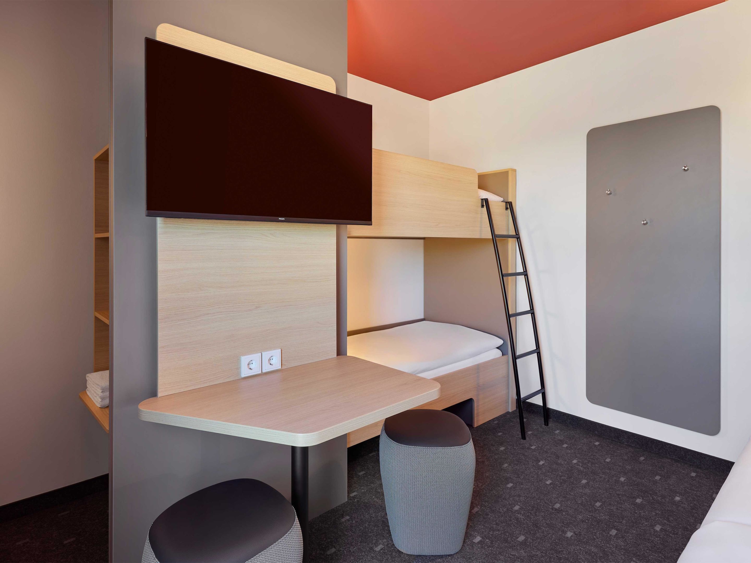 A compact room with a bunk bed, a desk, and a ladder.