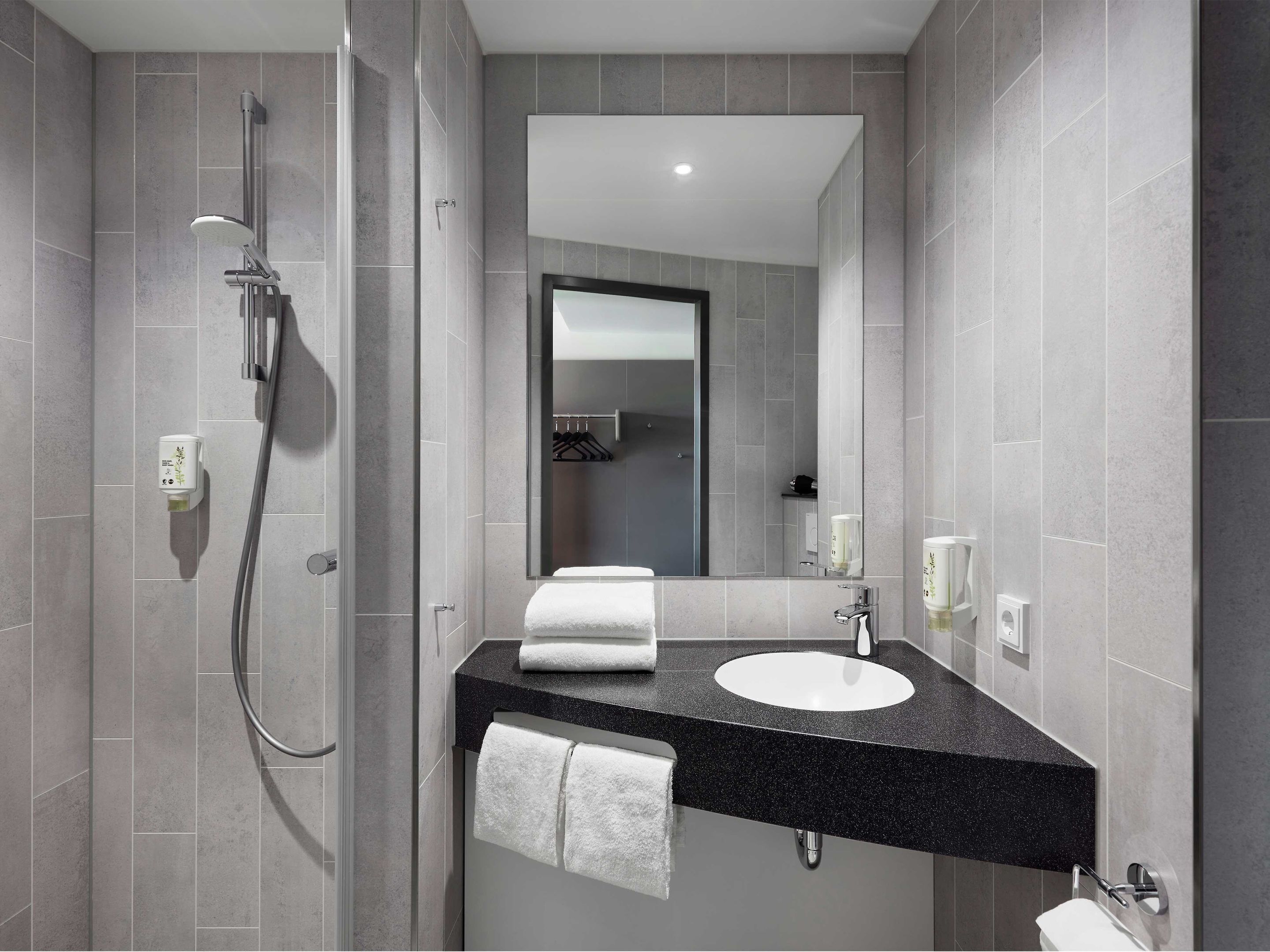 A modern bathroom with a shower, a sink, and a mirror.