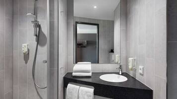 A modern bathroom with a shower, a sink, and a mirror.