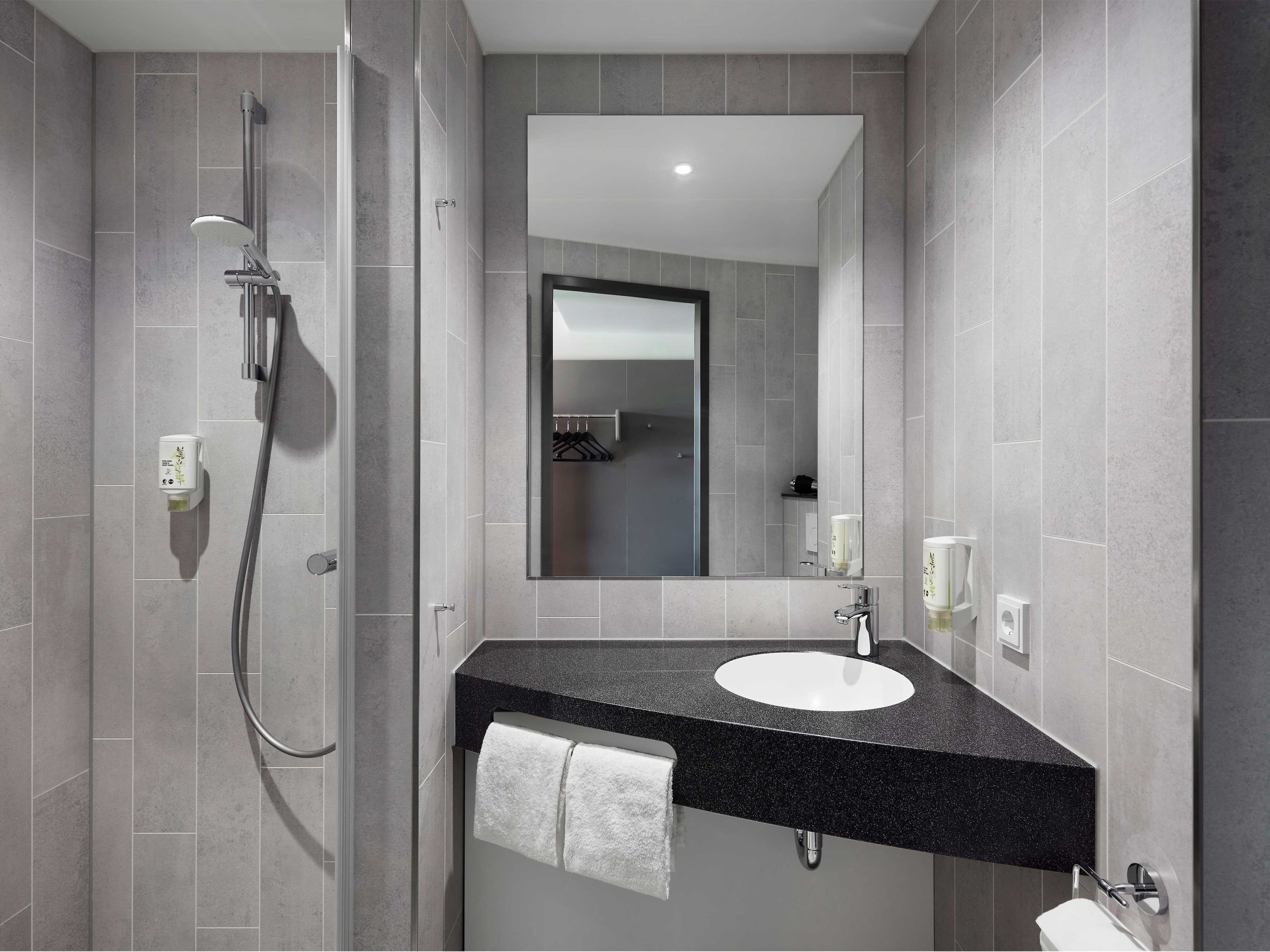 Un baño moderno con ducha, lavamanos y espejo.