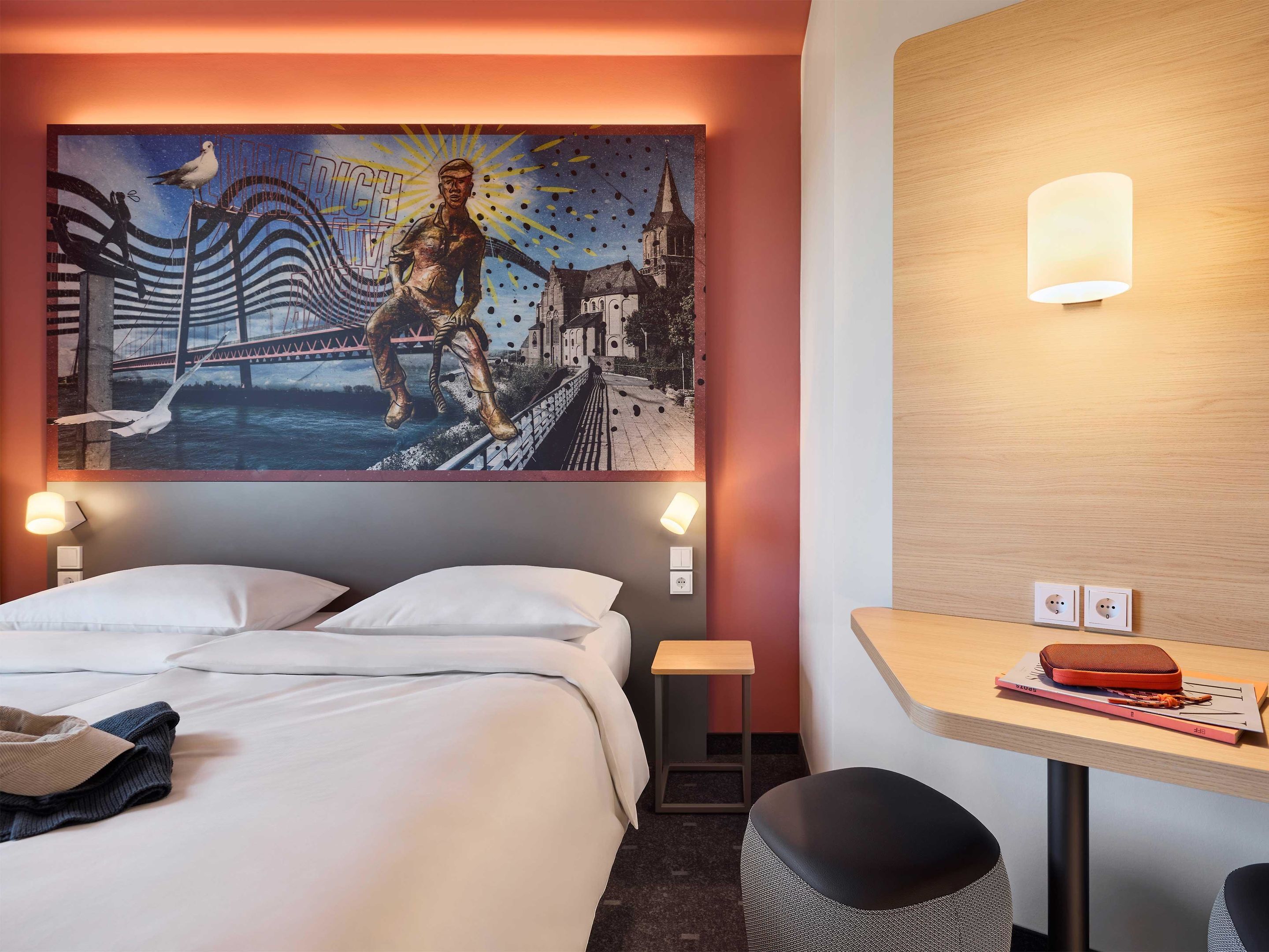 Een hotelkamer met een bed, nachtkastjes, een bureau en een wandeling schilderij.