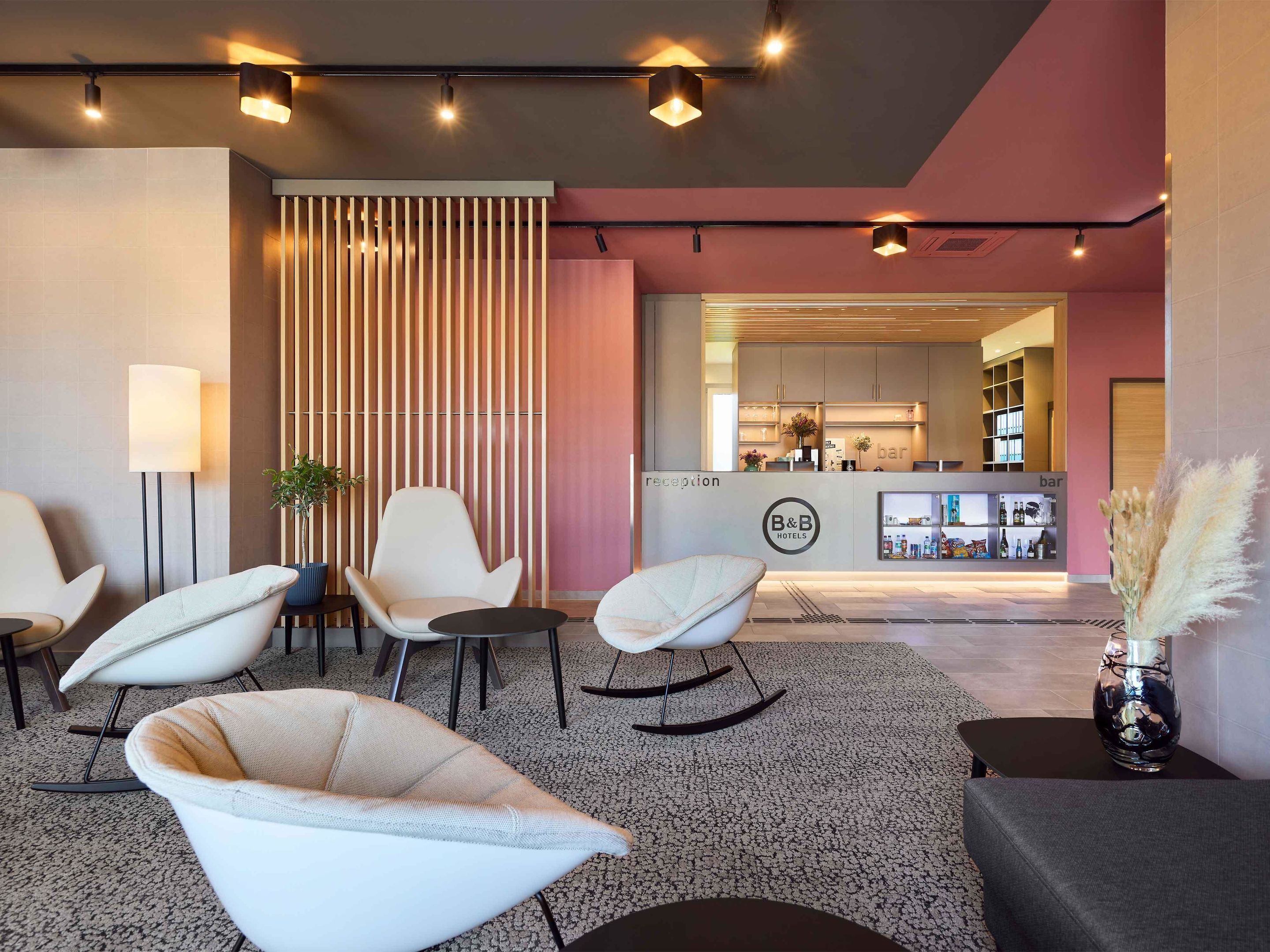 Un moderno vestíbulo de hotel con mostrador de recepción, zona de estar y bar.