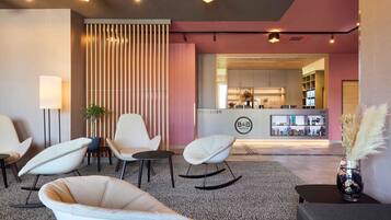 Un moderno vestíbulo de hotel con mostrador de recepción, zona de estar y bar.