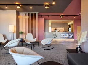 A modern hotel lobby with a reception desk, seating area, and bar. - B&B HOTEL Emmerich (Emmerich)