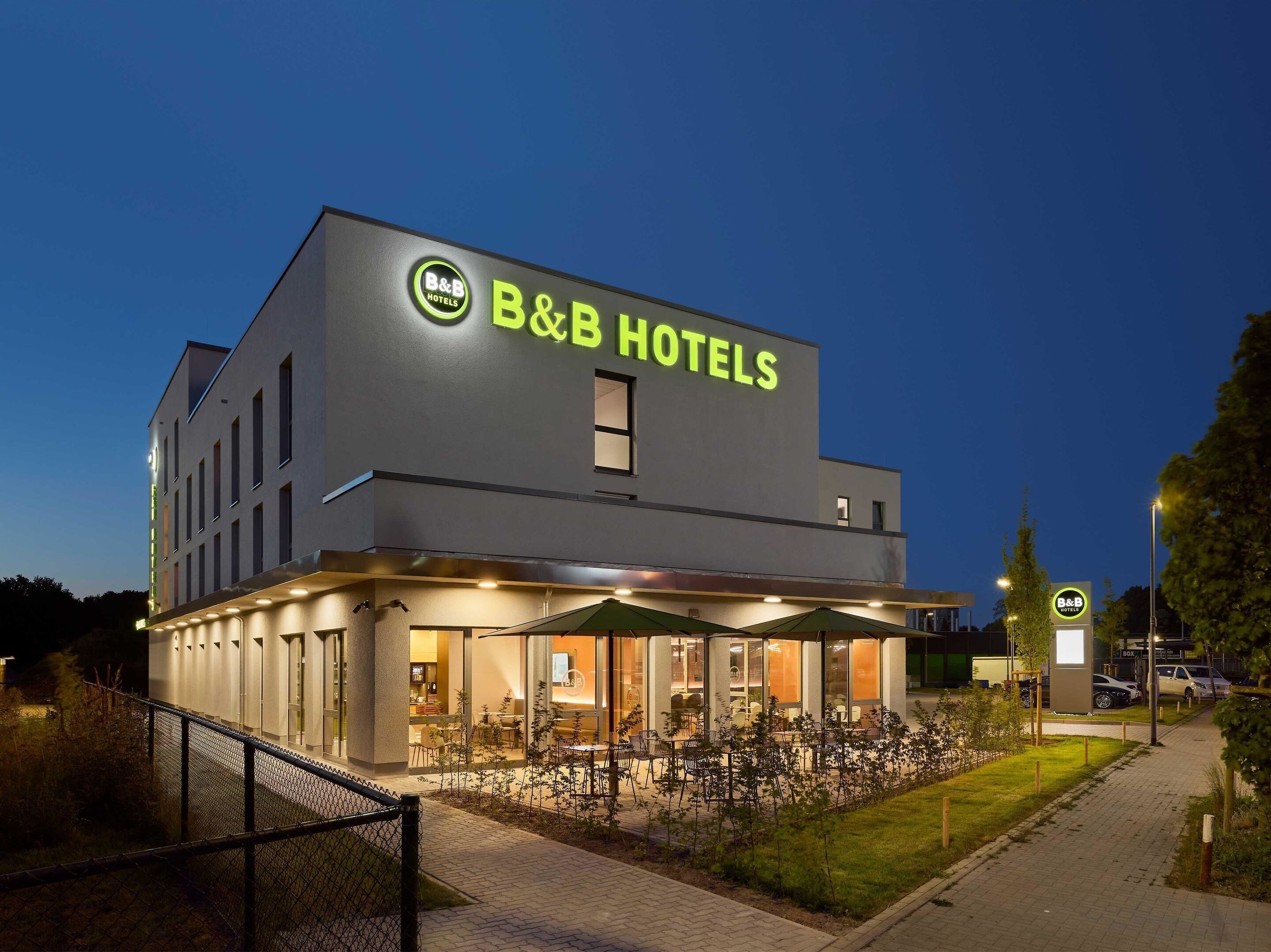 Un hotel B&B con diseño moderno, zona de estar exterior e iluminación en la entrada.
