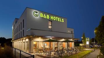 Un hotel B&B con diseño moderno, zona de estar exterior e iluminación en la entrada.