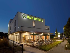 Een B&B hotel met een modern design, een buiten zitgedeelte en een goed verlichte entree.