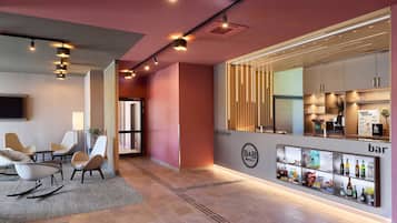 Een moderne hotellobby met een receptiebalie, zithoek en bar.