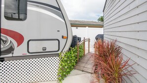 Uma casa com cerca branca e deck de madeira que dá para a porta da frente, ao lado de uma caravana.
