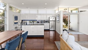 Una cocina moderna con armarios blancos, una mesa de comedor de madera y sillas azules.