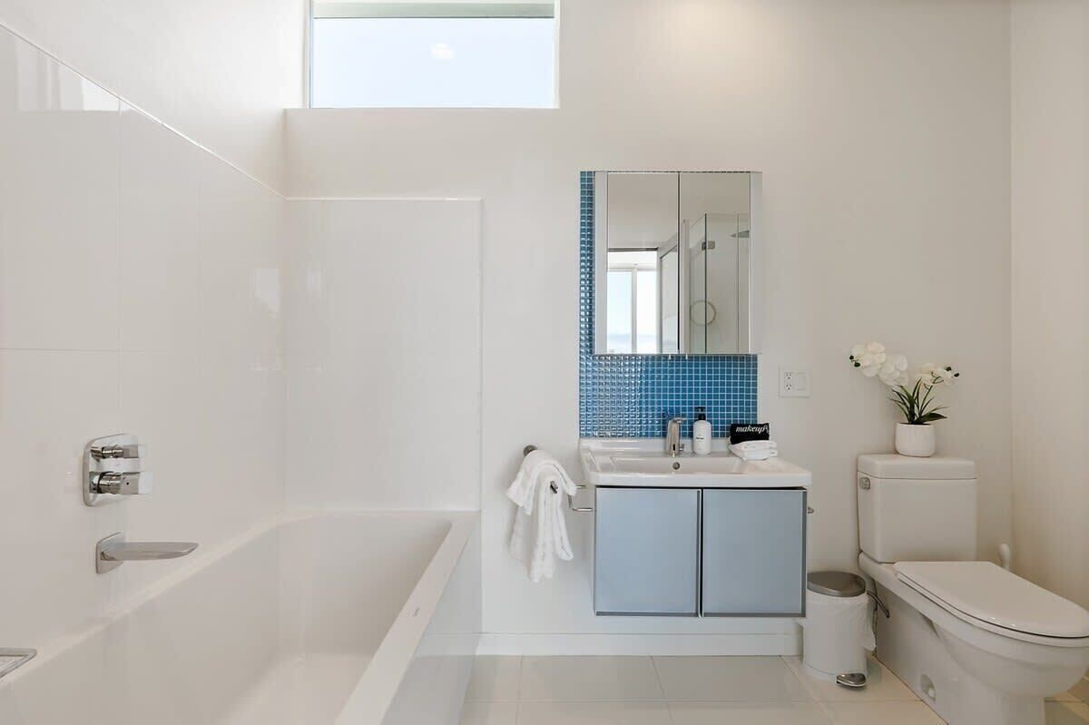 Un baño moderno con bañera, lavamanos con espejo y retrete.