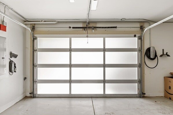 A garage with a white door, a fire extinguisher, and a coiled hose on the wall. - @ Marbella Lane - Cozy and Eccentric Design Home (Pacifica)