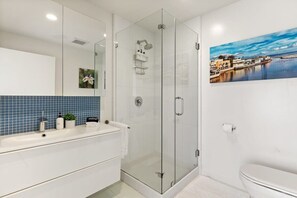 A modern bathroom with a glass-enclosed shower, a white sink with a blue-tiled backsplash, and a toilet. - @ Marbella Lane - Cozy and Eccentric Design Home (Pacifica)