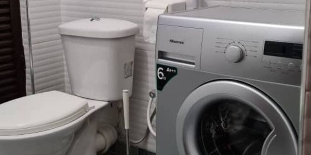 A compact bathroom with a white toilet, a washing machine, and a towel rack.