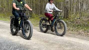 Twee personen fietsen op een grindpad, omringd door bomen.