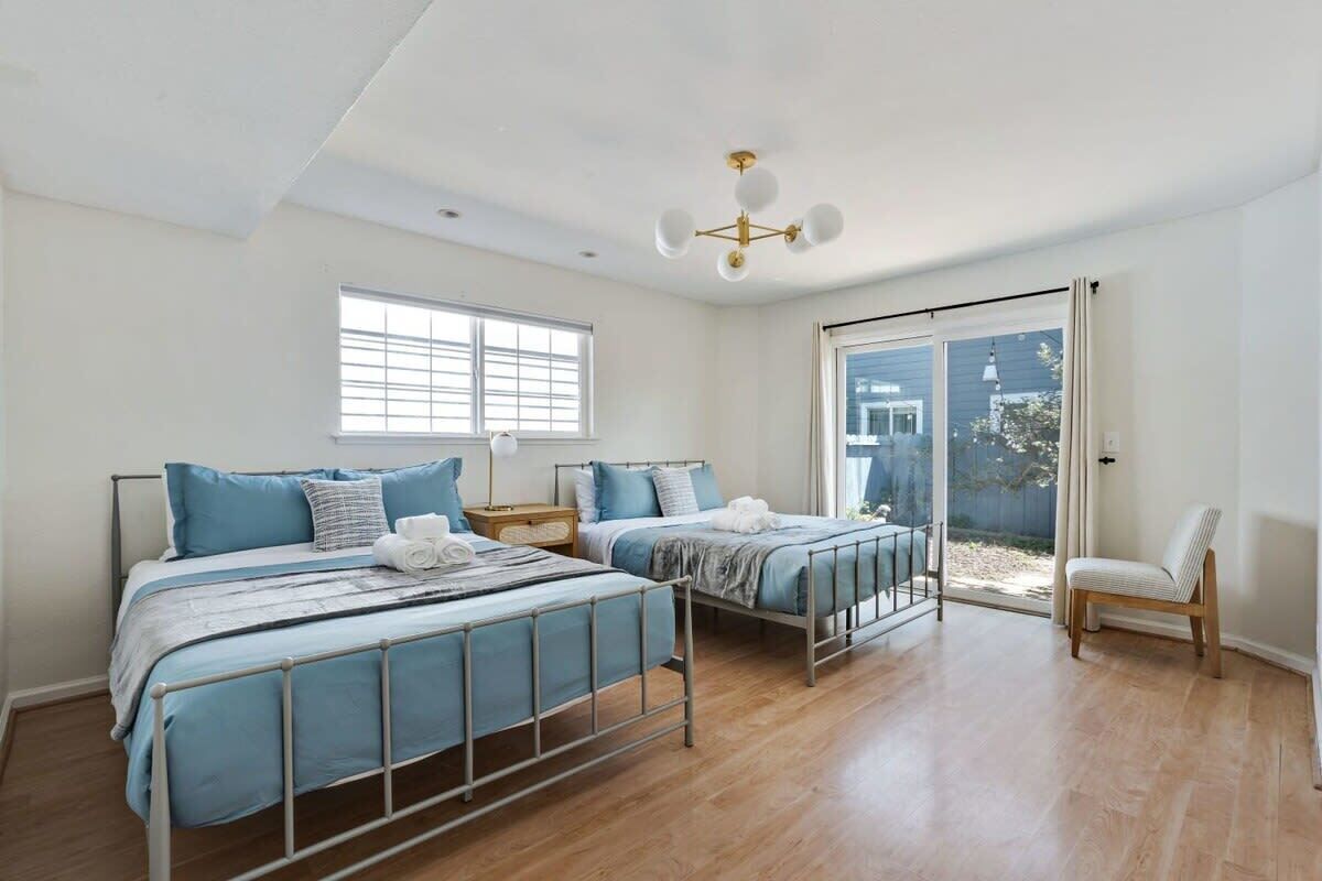 Un dormitorio con dos camas, una silla, un ventanal y una lámpara en el techo.