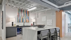 A modern kitchen with a marble island, bar stools, and a colorful abstract painting. - Modern Studio, Gym, Near UAB (Birmingham)