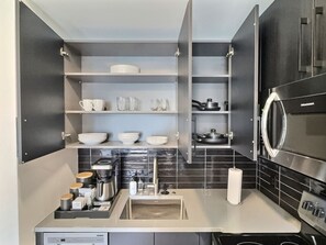 A modern kitchen with built-in appliances, open shelving, and a countertop with various kitchen items. - Stylish Studio, Walk to Food, Bars and Baseball (Birmingham)