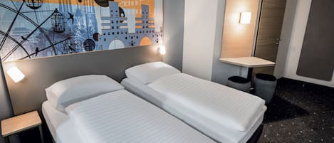 Habitación de hotel con dos camas, un mural en la pared, una mesita de noche y un espejo.