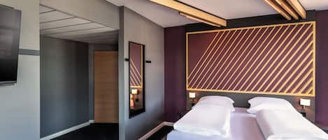 Une chambre d’hôtel moderne, dotée d’un lit, de tables de chevet, d’un grand miroir et d’un décor mural géométrique original.