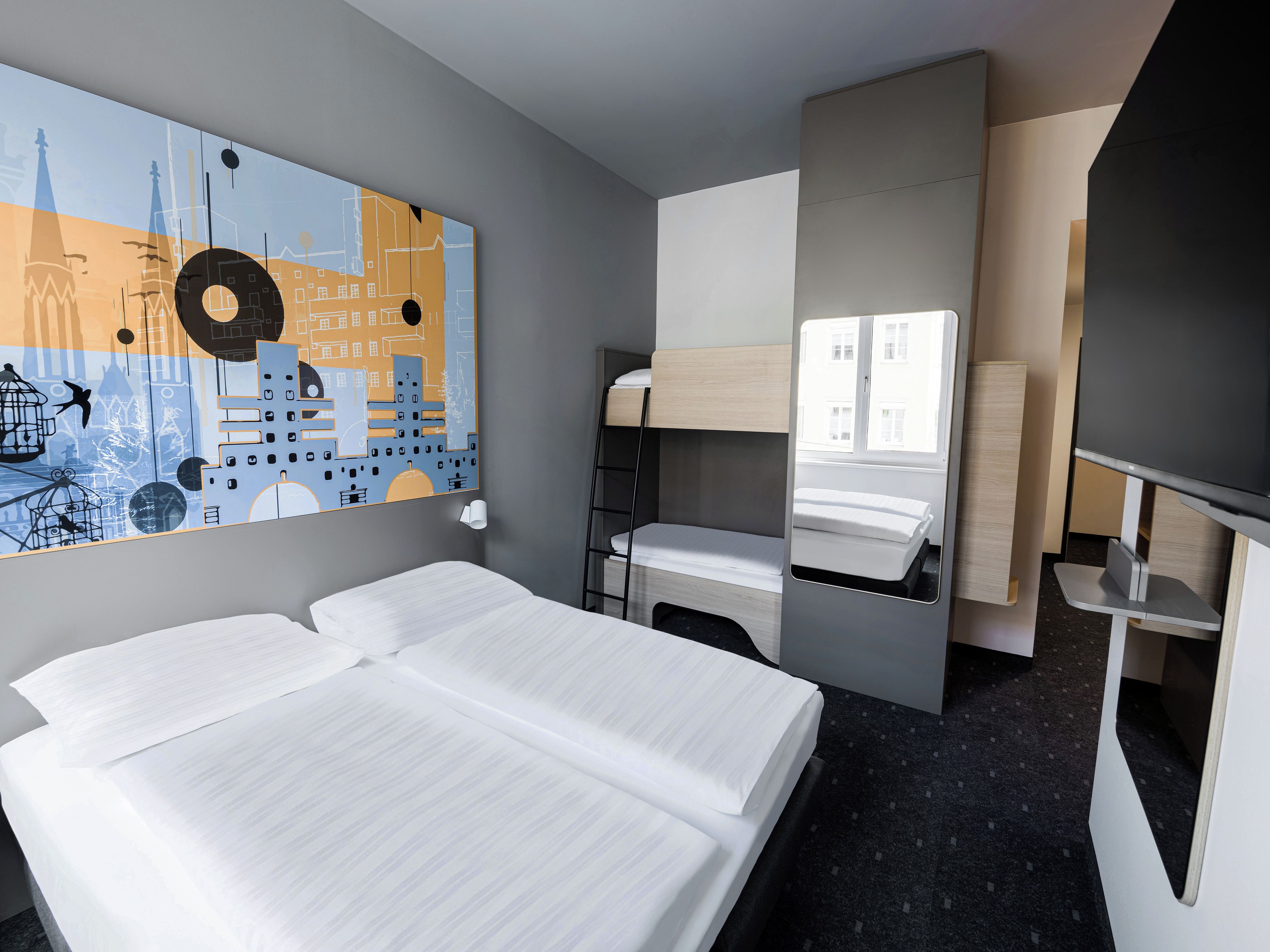 Habitación de hotel con cama, espejo, un cuadro con un paisaje urbano y una ventana.