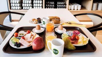 A breakfast tray with eggs, toast, fruit, and juice in a hotel setting.