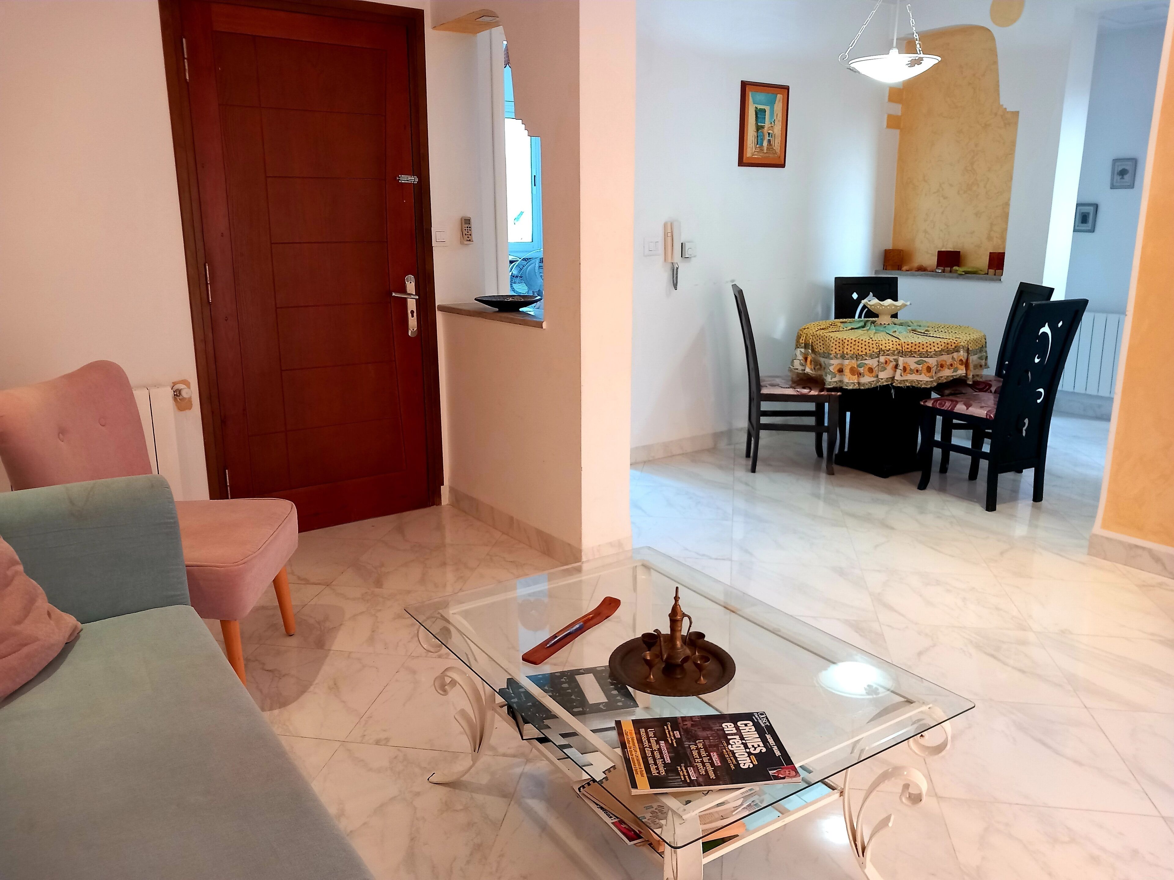 Un salon comprenant une table basse en verre, un canapé et un coin repas avec une table et des chaises.