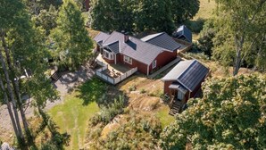 Een groot huis met een ruime achtertuin, omringd door bomen.