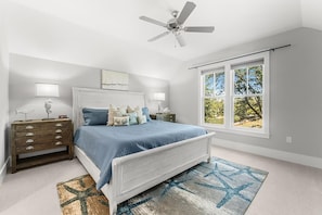 A bedroom with a bed, nightstands, a ceiling fan, and a large window. - Pineapple & Palms (Santa Rosa Beach)