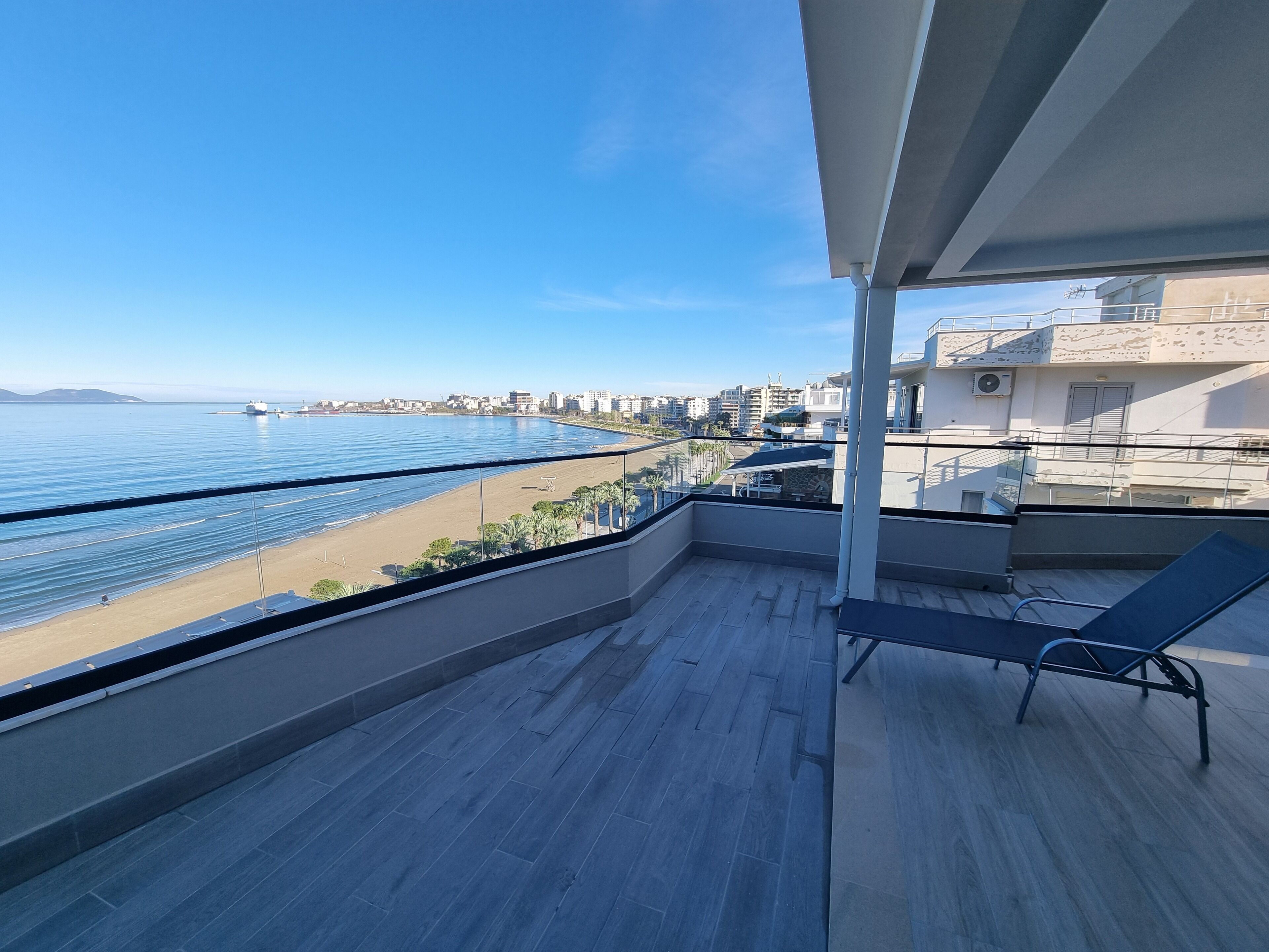 A balcony with a view of the sea and a cityscape.